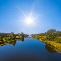 Obraz premium irrigation channel under a sparkle sun, summer irrigation engineering scene