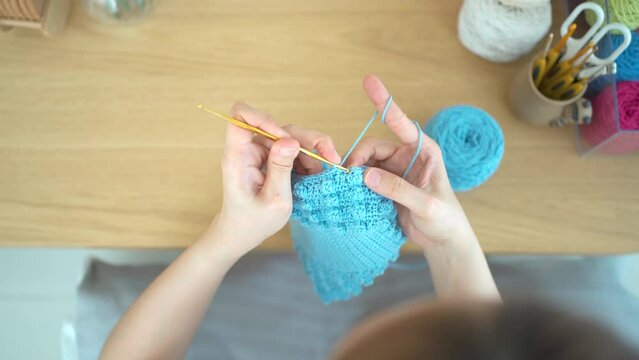 Happy cheerful Asian woman doing a crochet in living room in free time. 