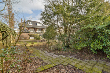 the back garden with some plants and trees in it, including an old brick path leading up to the house