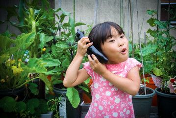 Young asian girl holding eggplant from home container vegetable garden