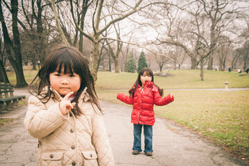 Two young asian girls in winter outfit posing in big park in winter