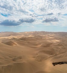 Beautiful view of sand dunes in the desert against a backdrop of a blue sky with white clouds
