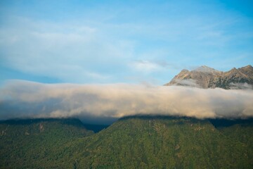 Majestic mountain range illuminated by the sun, with light clouds scattered across the landscape