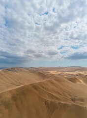 Beautiful view of sand dunes in the desert against a backdrop of a blue sky with white clouds