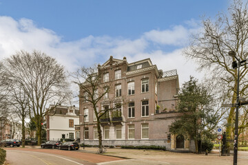 Naklejka premium an old brick building in the middle of a street with trees and cars parked on the side of the road