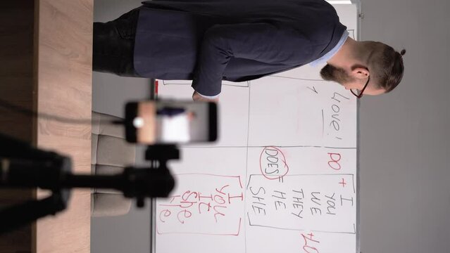 English teacher recording video lesson for his social media blog using smartphone. Filming educational video for internet audience. Vlogging, tutoring, education concept