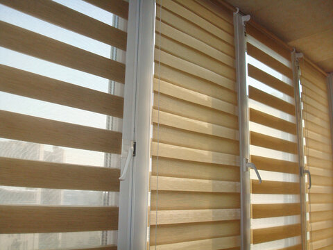 Double roller blinds closeup on the window in the interior. Dual roller shades beige color close-up. Zebra blinds. Duo system day and night.