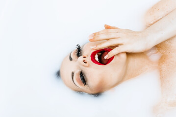 Portrait of beauty sexy woman with bright red lips relaxing in milk bath. Beautiful Fashion model girl taking milk bath, spa and skin care concept