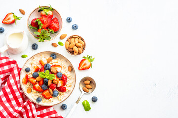 Oatmeal porrige with fresh berries and nuts on white.