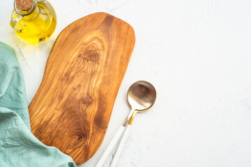 Obraz premium Olive board, olive oil, spoon and tablecloth on white kitchen table. Food background with copy space.