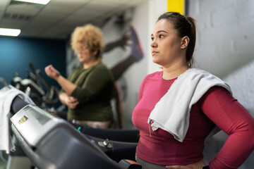 Two beautiful, overweight women power through a fitness routine, determined to achieve their goals, and one of them lose her confidence. Workout on the treadmill.