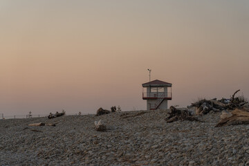 A pebble beach with snags of trees and a rescue booth. Evening on the coast of the Gulf of Finland...