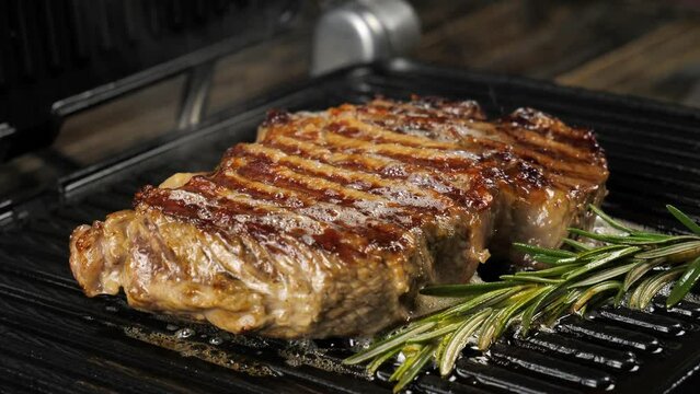 Delicious juicy meat steak cooked on the grill.Cooked juicy beef steak with rosemary and garlic on an electric grill