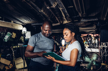 Professional Car Mechanic is Investigating Under a Vehicle on a Lift in Service. Auto Service Worker Checking Car Under Carriage Look For Issues. Car service technician check and repair customer car.