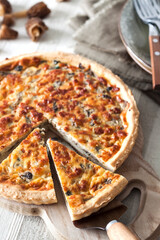 Quiche – open tart pie with morel mushrooms, onion and cheese on wooden cutting board