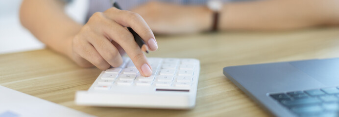 Businesswoman presses a calculator to calculate earnings and analyze company earnings in his private office, Information in finance and accounting, Company performance and revenue.