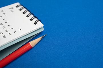 close up of calendar and red pencil on the blue table background, planning for business meeting or...