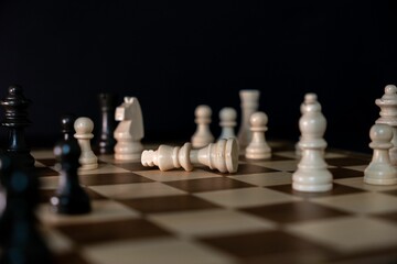 A dramatic depiction of the fallen white king chess piece on a chessboard