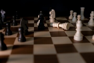 A dramatic depiction of the fallen white king chess piece on a chessboard