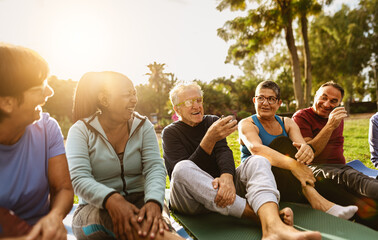 Happy multiracial senior friends drinking a tea after workout activities in a park - 595062016