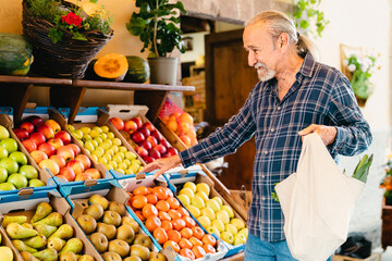 Happy senior man buying fresh fruits at the market - Shopping food concept