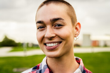Happy young woman with shaved head posing and smiling in front of camera