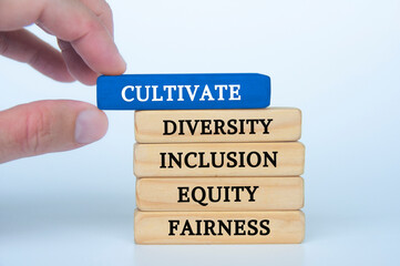 Hand holding blue wooden block with text - cultivate diversity, inclusion, equity and fairness....