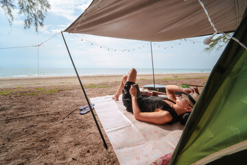 asian man camping and relax on beach with sea background on summer vacation