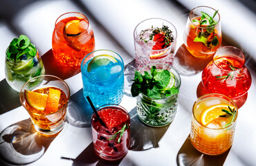 Summer cocktails drinks set. Assortment of multicolored strong and low alcoholic beverages for cocktail party. White background, hard light, shadows pattern, top view
