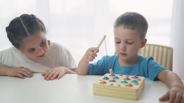 children at the table in kindergarten play an educational game fishing. development of fine motor skills dream in children. children play educational game catch fish in kindergarten. game kid concept
