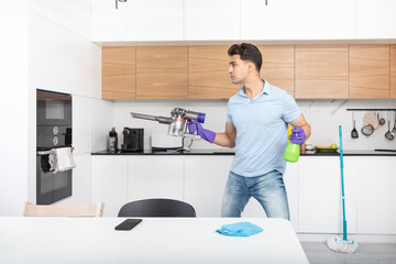 Young handsome man cleaning home. Attractive guy holding vacuum cleaner like a weapon in combat...