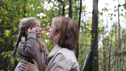 Hello September. A young mother and little daughter walk in the city park in autumn.