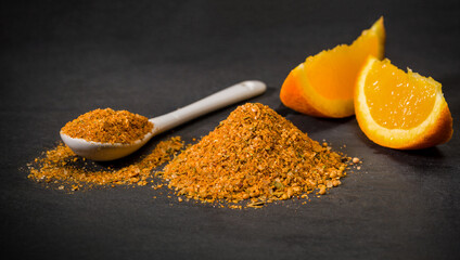 Dried orange spice. Spoon and a pile of ground grilled orange. Fresh cut sliced. Spices for recipes.