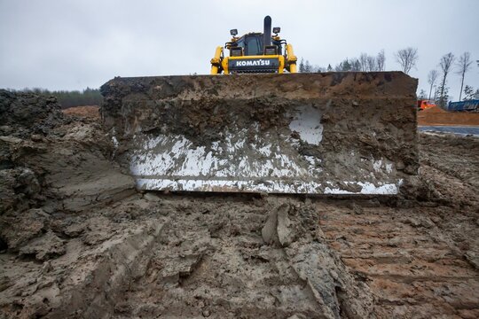 Ust-Luga, Leningrad oblast, Russia - November 16, 2021: Groundworks on construction site. Komatsu dozer on dirty ground. Closeup photo of muddy steel blade