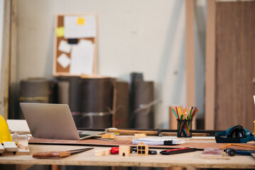 Working table of carpenter working desk in factory with laptop and tools.