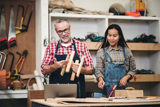 Carpenter man woodwork factory owner and assistant working in wood workshop looking on lapop for new online order, Small business entrepreneur woking together at workplace.