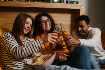 A group of friends watch a comedy movie sitting on soft bean bags with drinks and snacks.