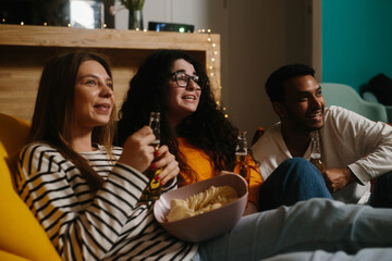 Young woman with friends watching movie in cinema and laughing. Group of people in the theater with chips and drinks.