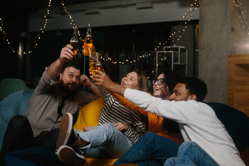 A group of friends have fun together in a cafe in the evening, drink beer and chat.