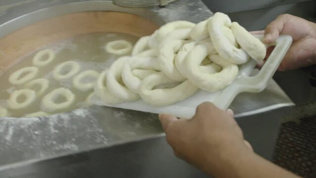 Bagel making in Montreal, a man boiling bagels in honey water