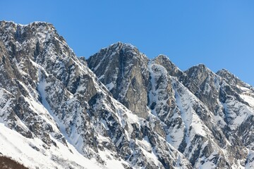 Majestic mountain range blanketed in freshly fallen snow under a brilliant blue sky.