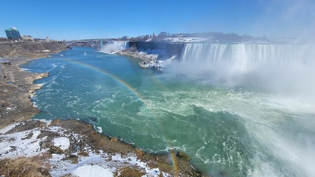 a large waterfall is pictured with a rainbow near by it
