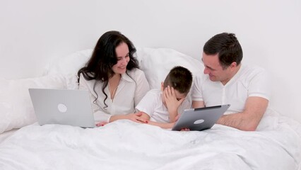 man woman boy spend time together in bed holiday vacation chat have fun relax look at tablet real people live conversation love at home happiness joy success in gadgets place for ad text happy family