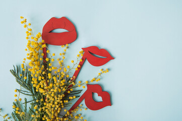 Greeting card Womens lips with flowers.. International Women's Day, Mother's Day, March 8 concept Mimosa branch on blue background close-up and copy space