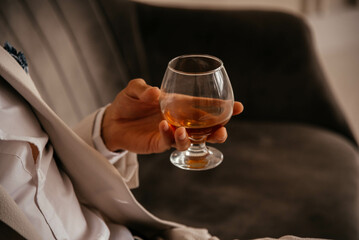 A glass of cognac in a man's hand. 