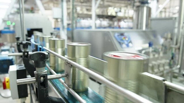 Tomato sauce cans on a conveyor belt in a canned food production facility