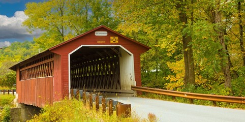 Silk Road covered bridge with trees showing fall colors near Paper Mill Village, Vermont.
