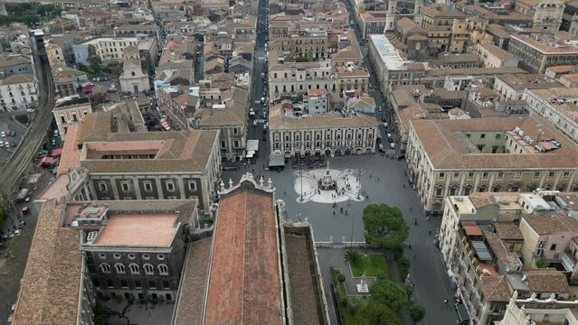 Drone 4K video travel aerial view Catania historical city center square Duomo with Catholic Cathedral of Saint Agatha and elephant statue made from lava Etna mountain, Sicily, Italy