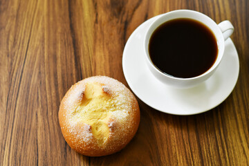 Pan dulce y taza de café sobre una mesa de madera. Pan de yemas. Espacio para texto al lado izquierdo.