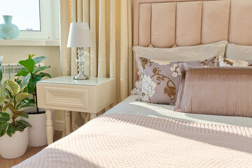 Classic bedroom interior in light ivory colors, in warm sunlight